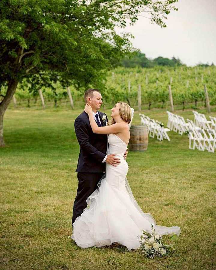 Newlyweds embracing beside vineyard rows