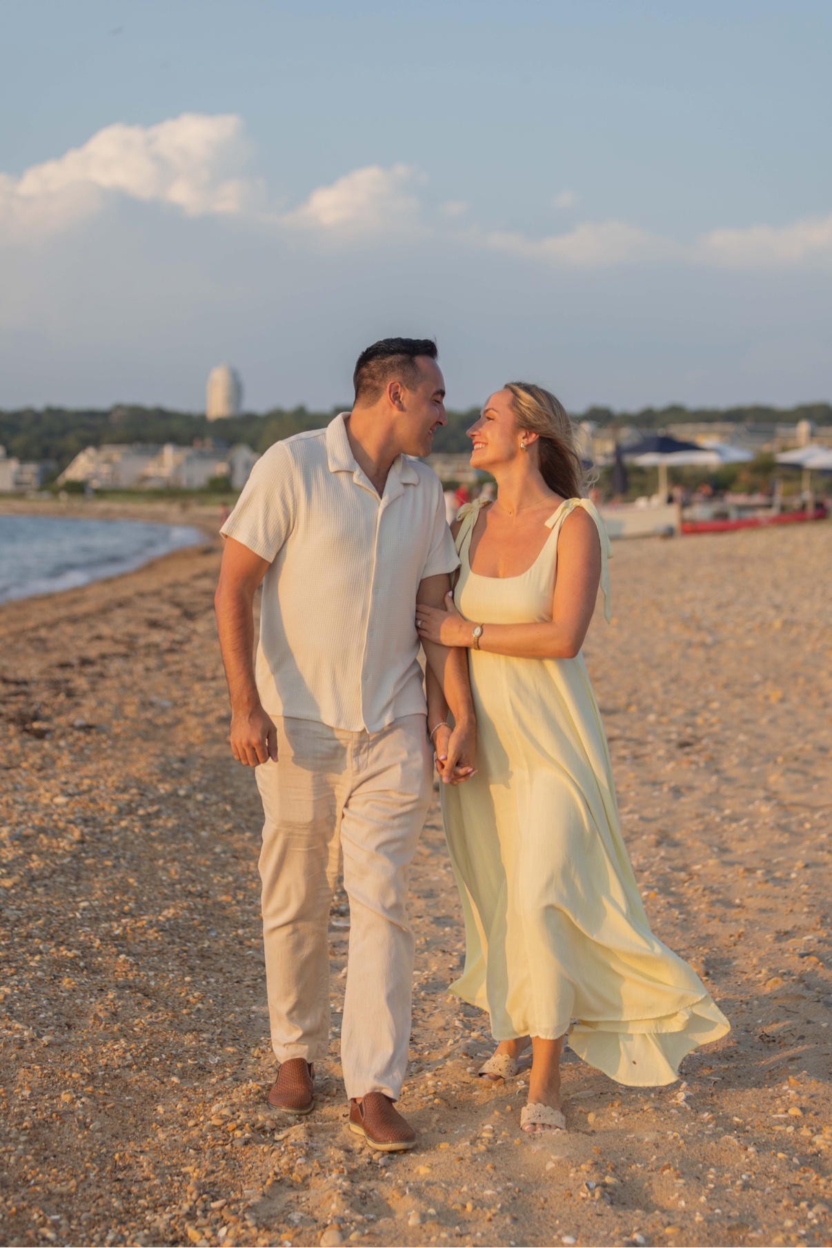 Engagement photos on a Long Island beach — a couple walking hand in hand at sunset