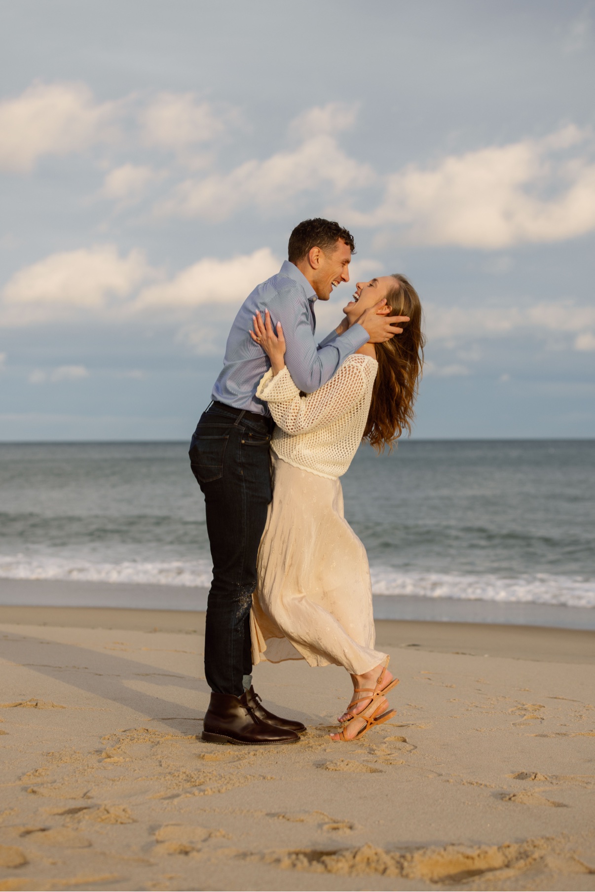 Groom-to-be dipping his fiancée for a kiss during engagement photos at a Long Island beach