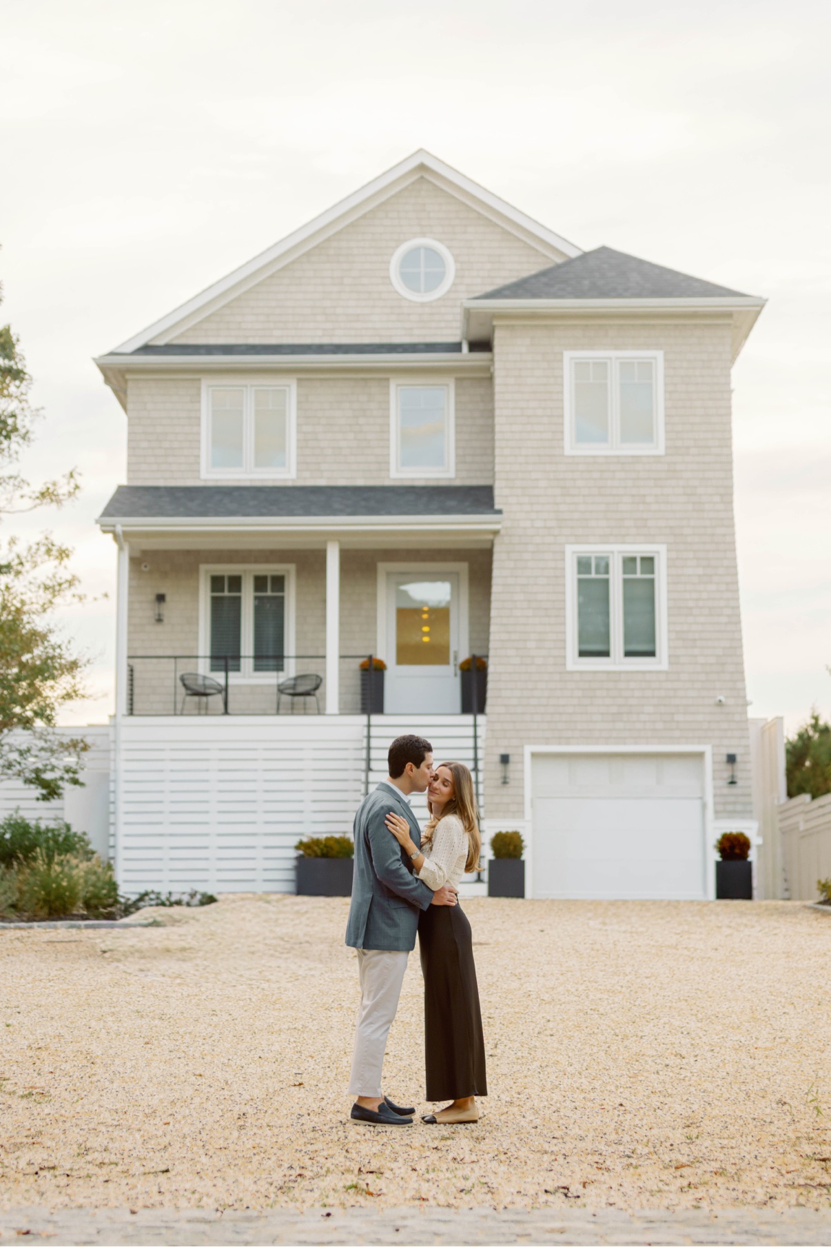 Engagement session in front of a Long Island beach house — a newly engaged couple embracing