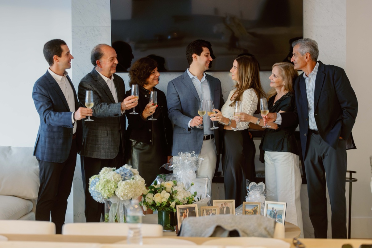 Family raising a champagne toast inside the beach house to celebrate the proposal