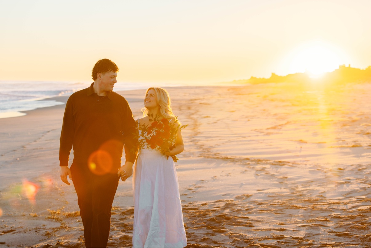 Engagement photos at Cooper's Beach, Southampton, Long Island — a couple walking hand in hand along the beach into the sunset just after the proposal