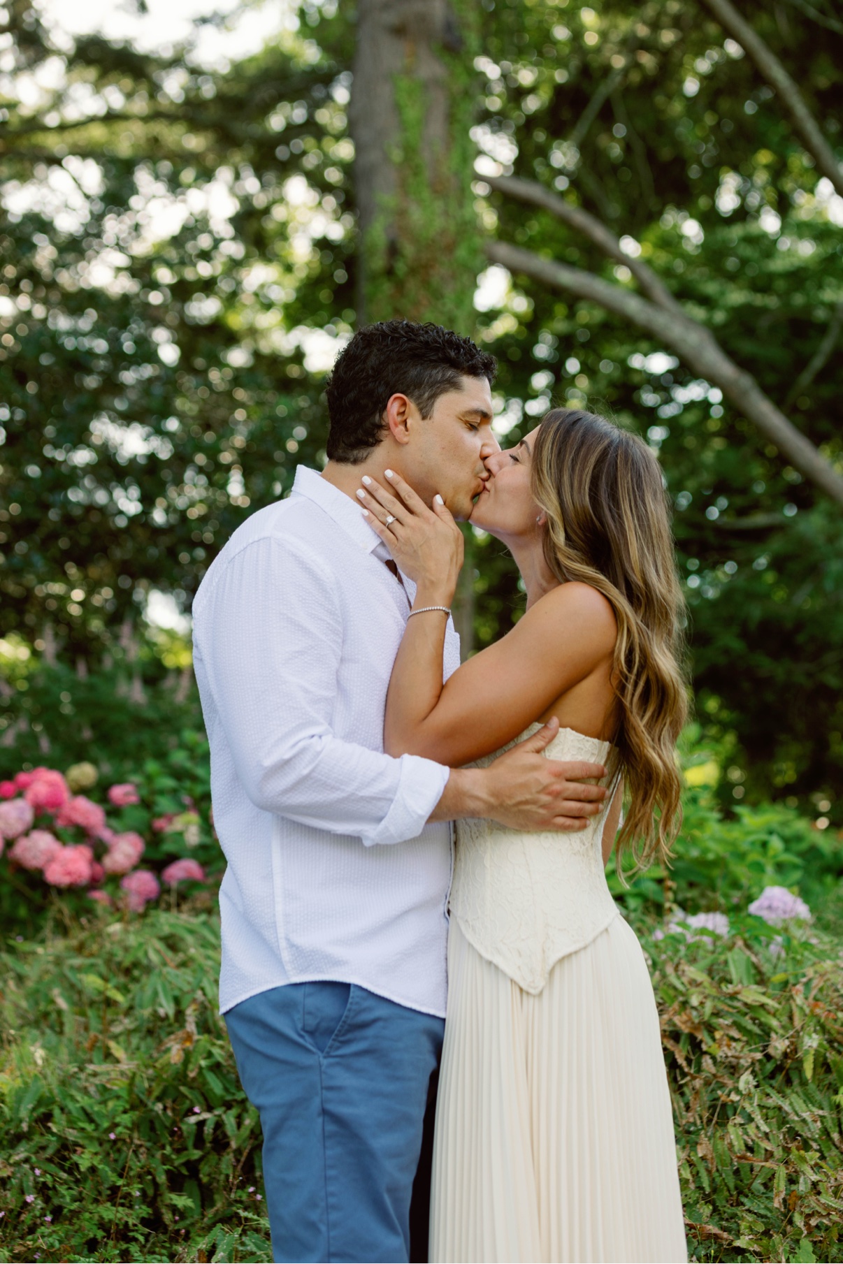Engagement session in a Long Island garden — a couple kissing among the hydrangeas