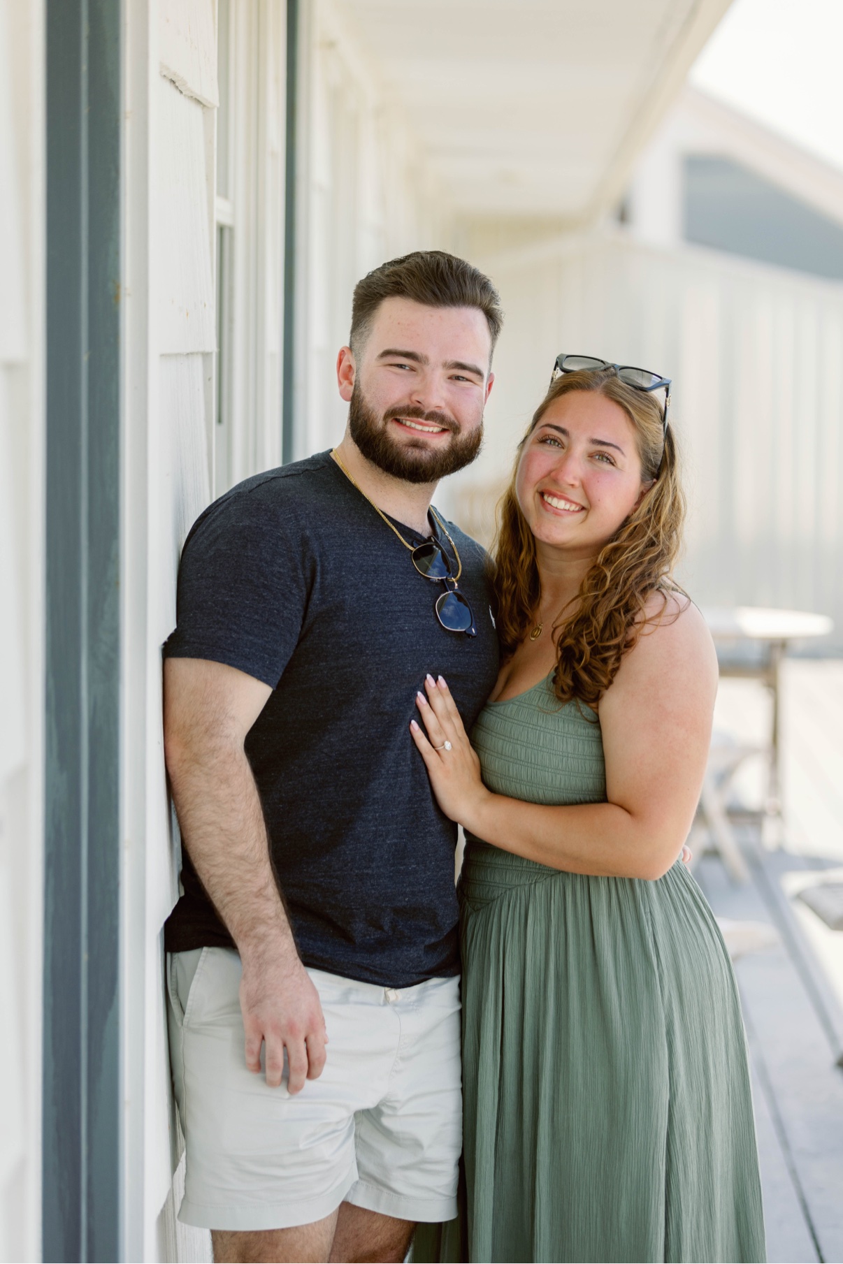 Smiling newly engaged couple posing on a porch during their Long Island engagement session
