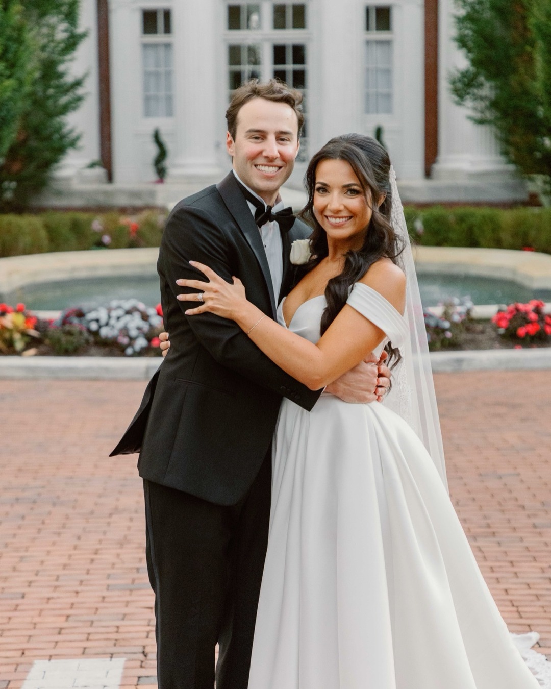 Newlyweds embracing in front of Bourne Mansion