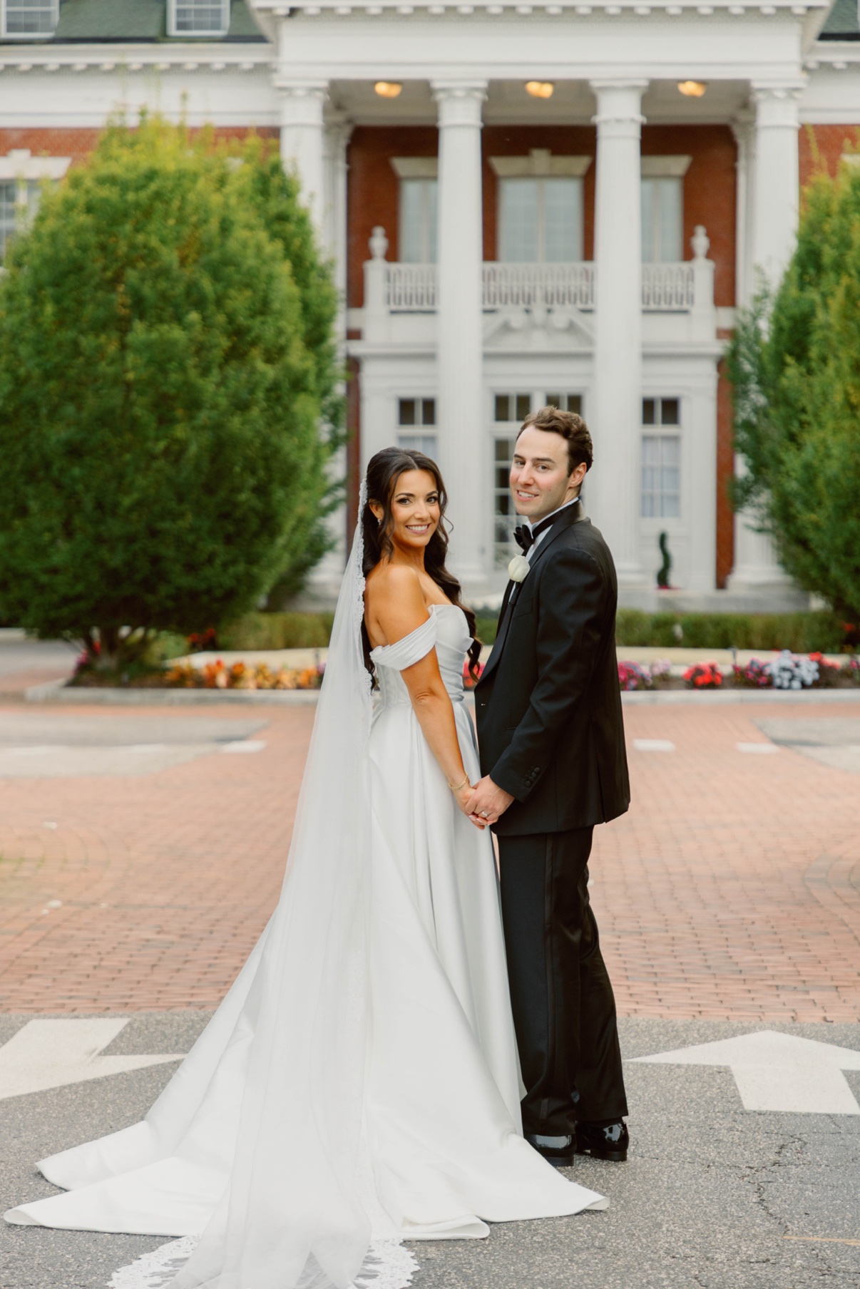 Newlyweds holding hands in the Bourne Mansion courtyard