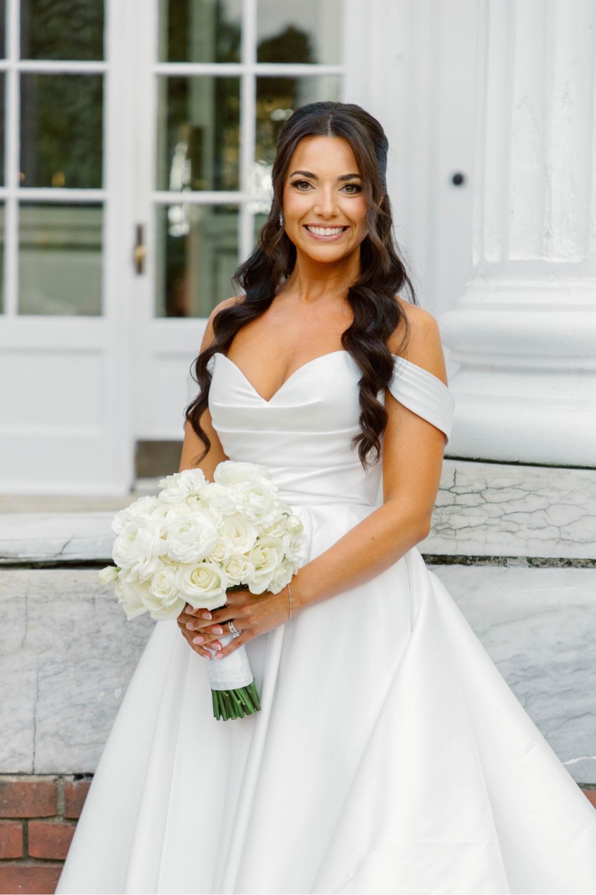 Bride holding white flowers outside Bourne Mansion