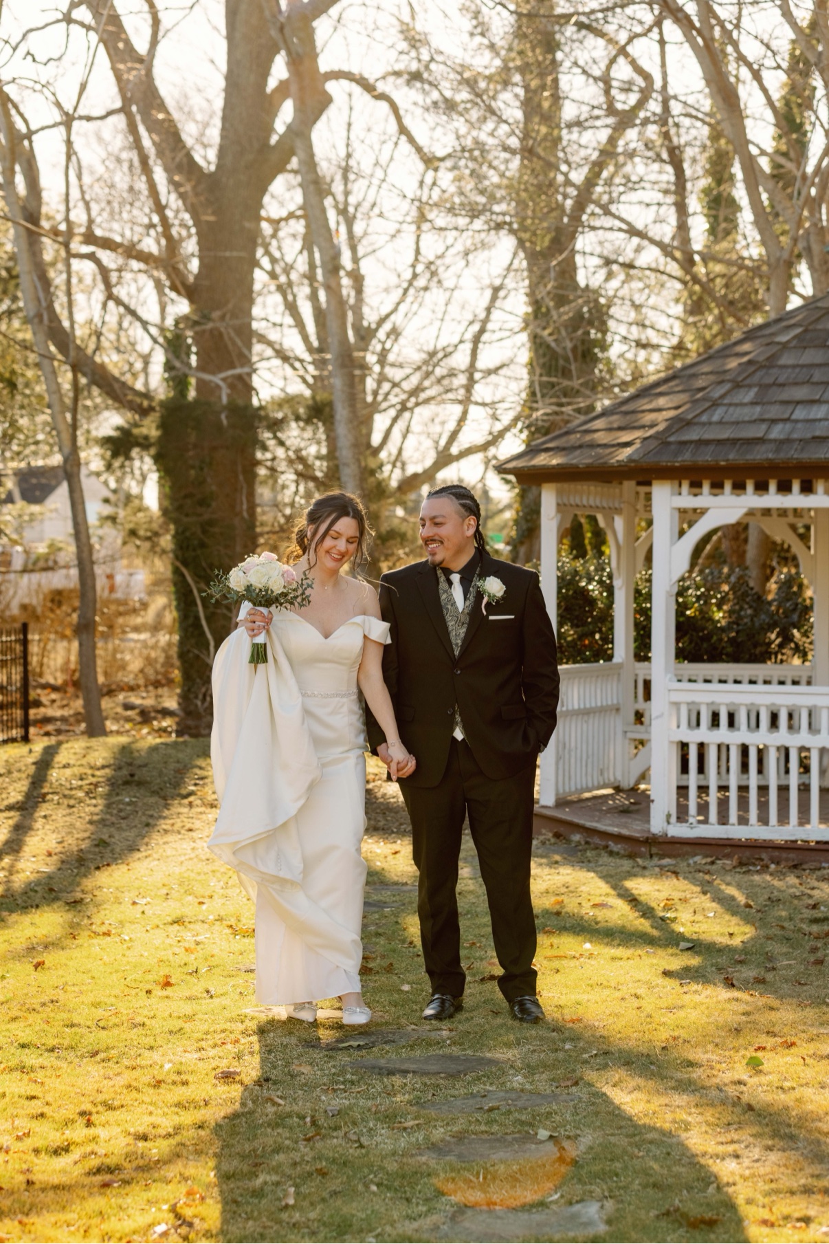 Newlyweds walking hand in hand past the gazebo