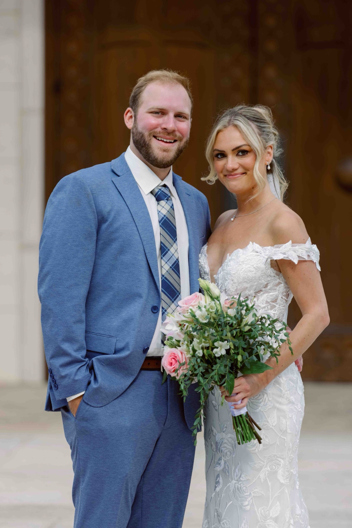 Samantha and James smiling together outside the wooden church doors at The Muses in Southampton