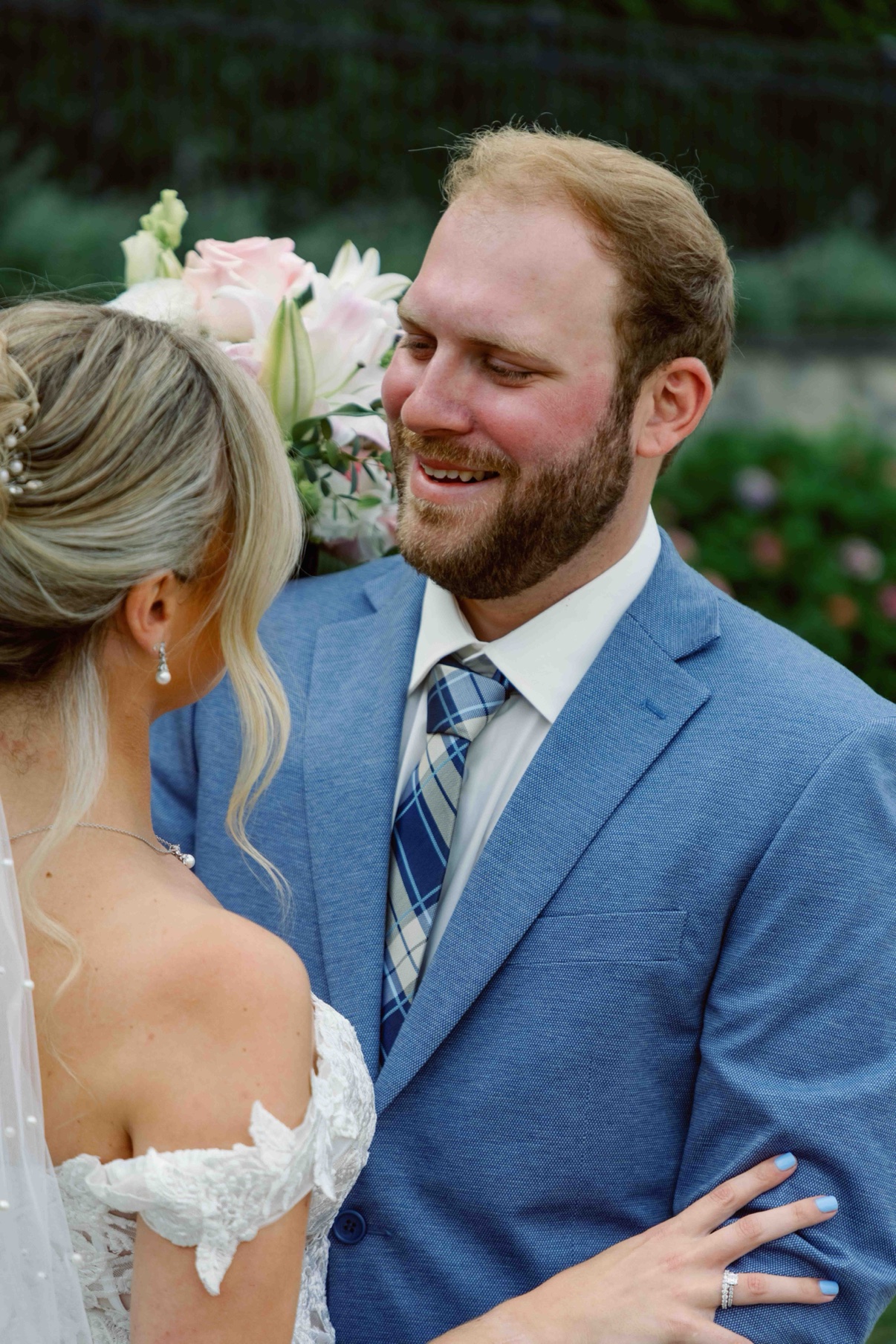 James smiling as he looks at Samantha, her bouquet between them at The Muses