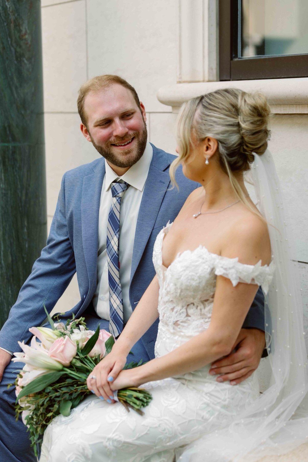 Samantha and James laughing together beside a green marble column at The Muses