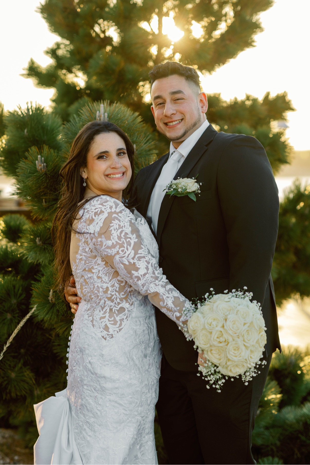 Newlyweds smiling together in sunset light by the water on Long Island