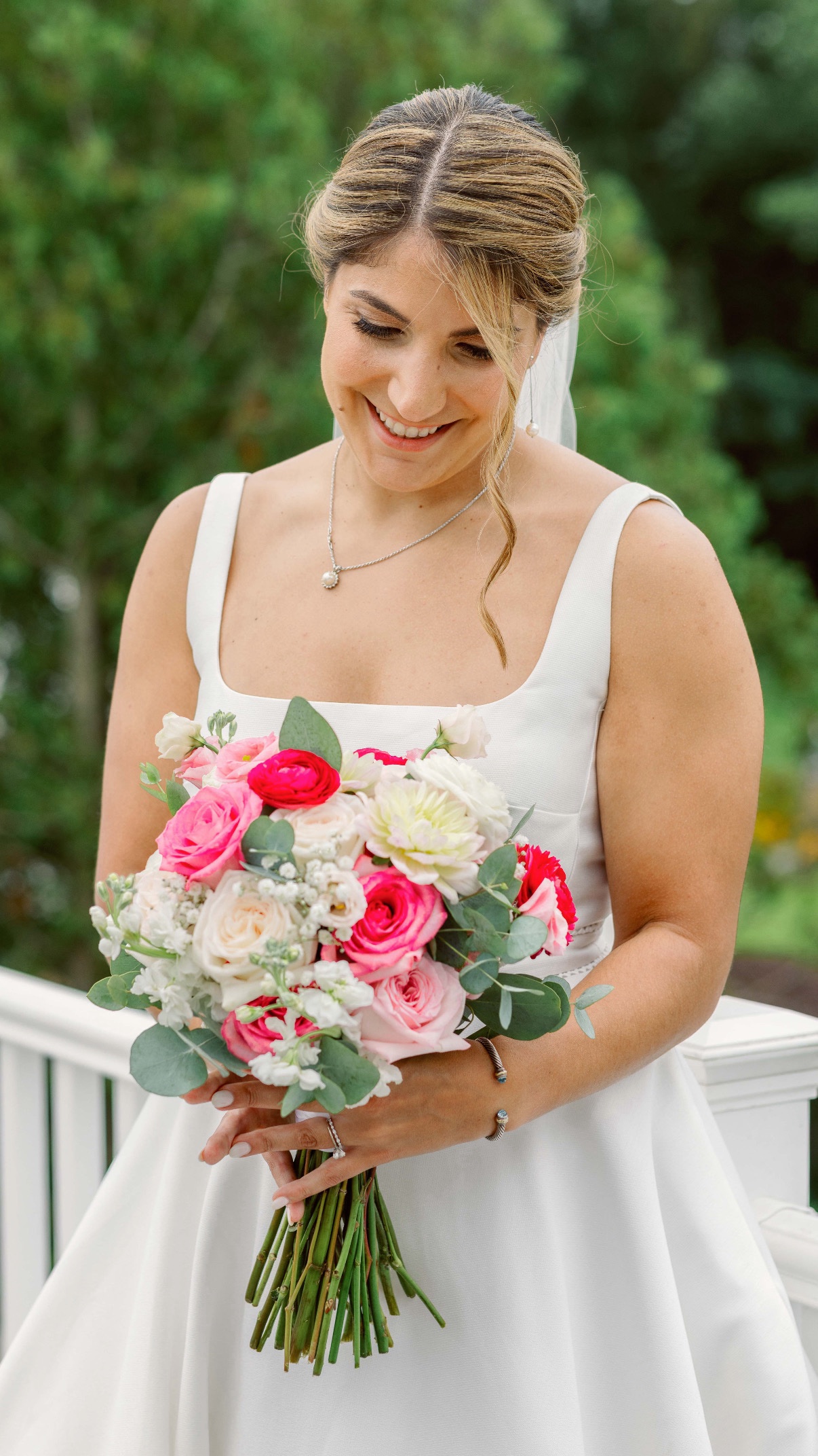 Smiling blonde bride holding a pink and red bouquet