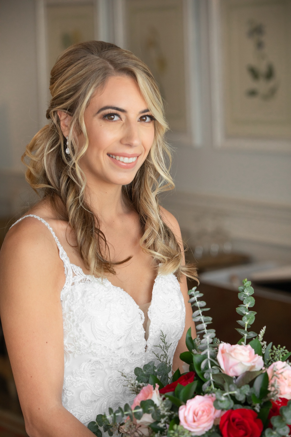 Smiling blonde bride holding a pink and red rose bouquet at Vineyards at Aquebogue