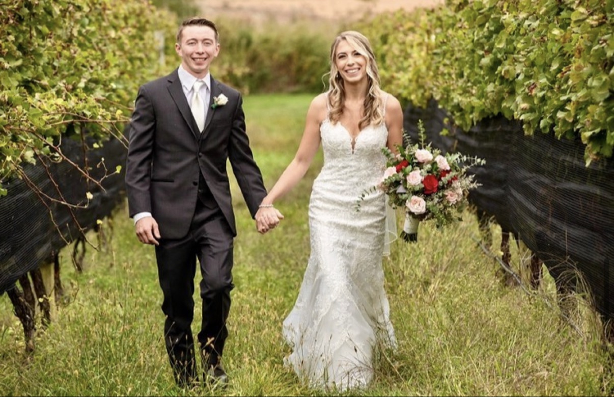 Newlyweds walking together beside vineyard rows